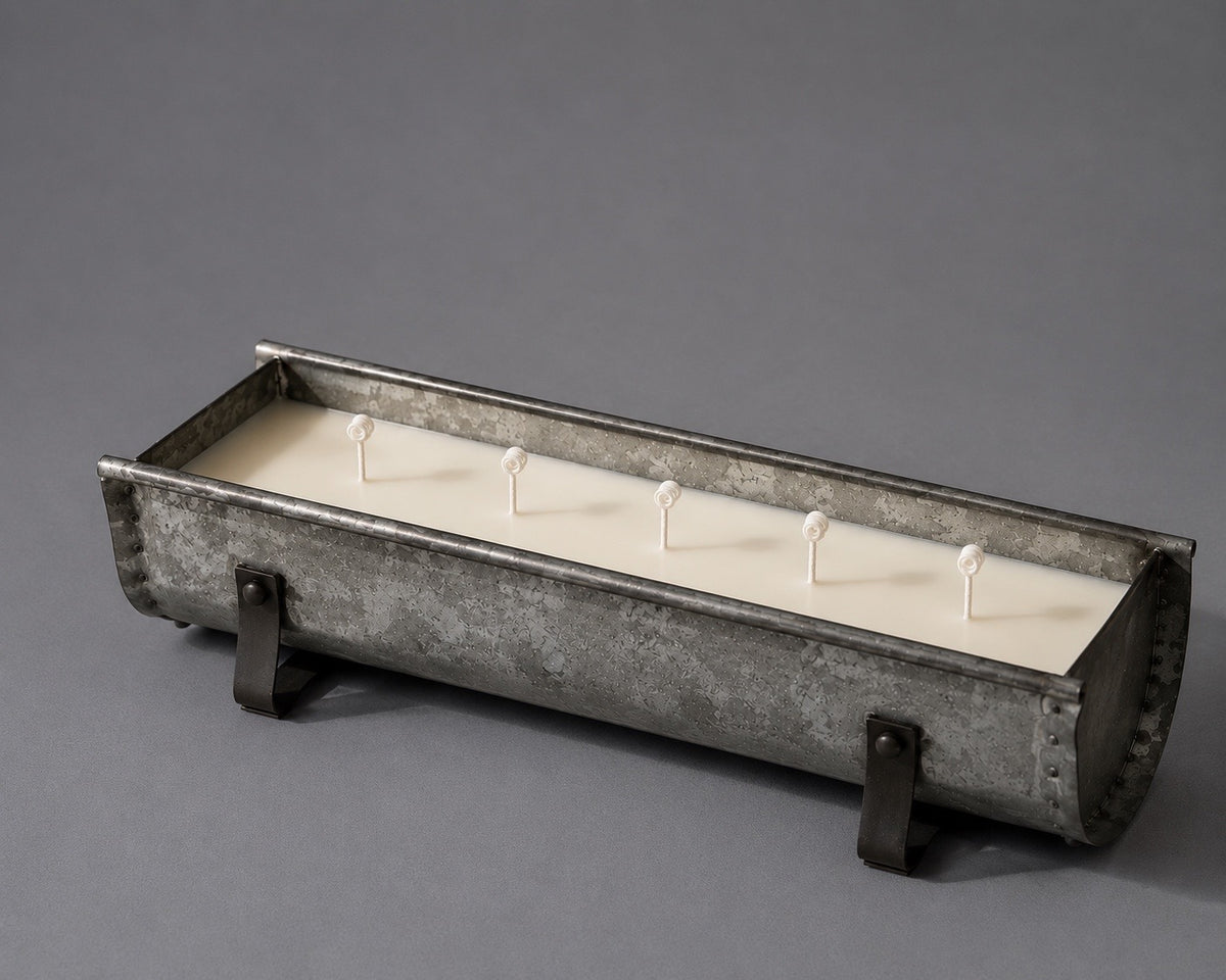 Long rustic galvanized-metal trough filled with ivory wax and a row of wicks