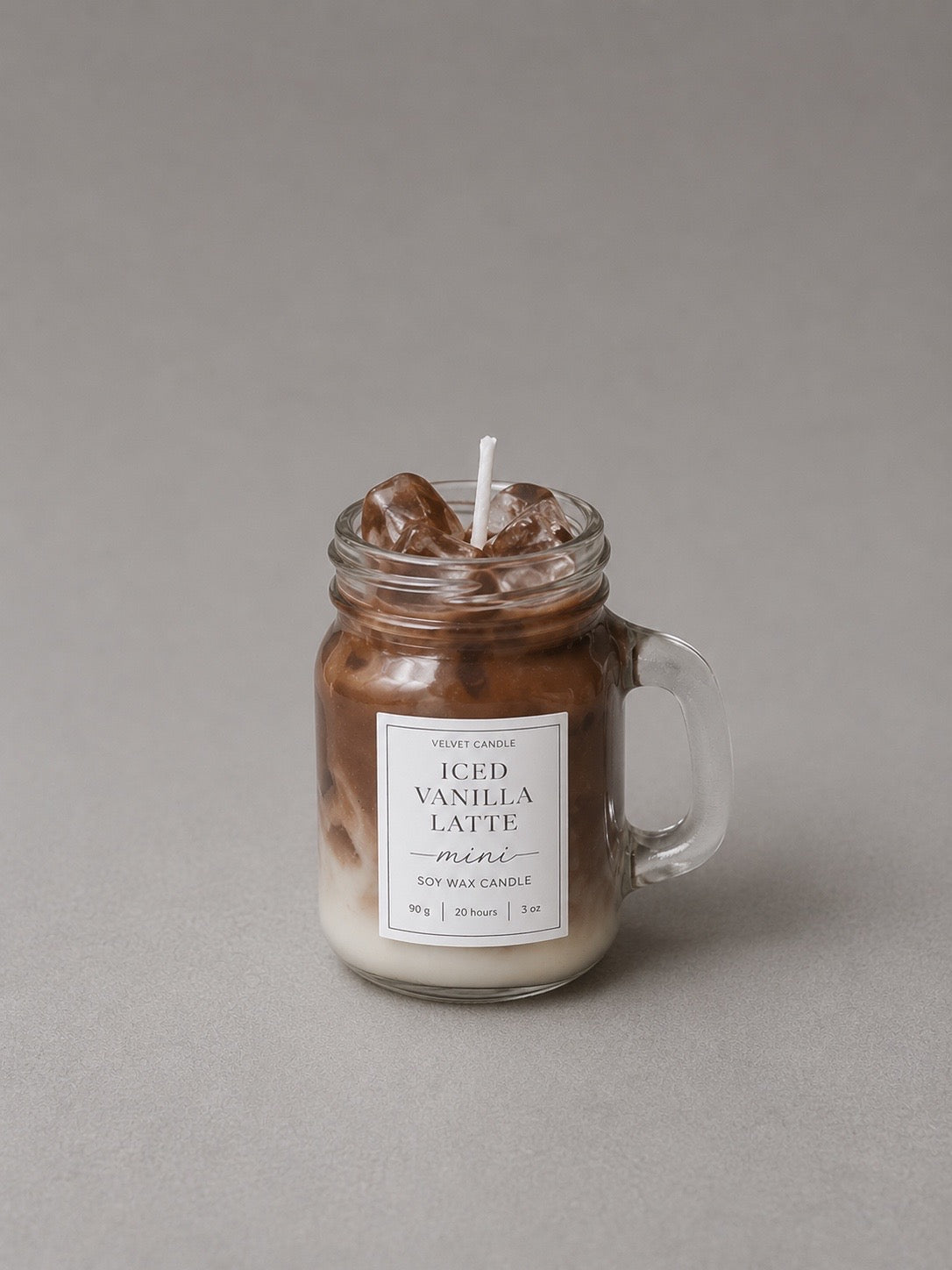 Mini iced coffee candle with cream and brown wax layers in a handled glass mug