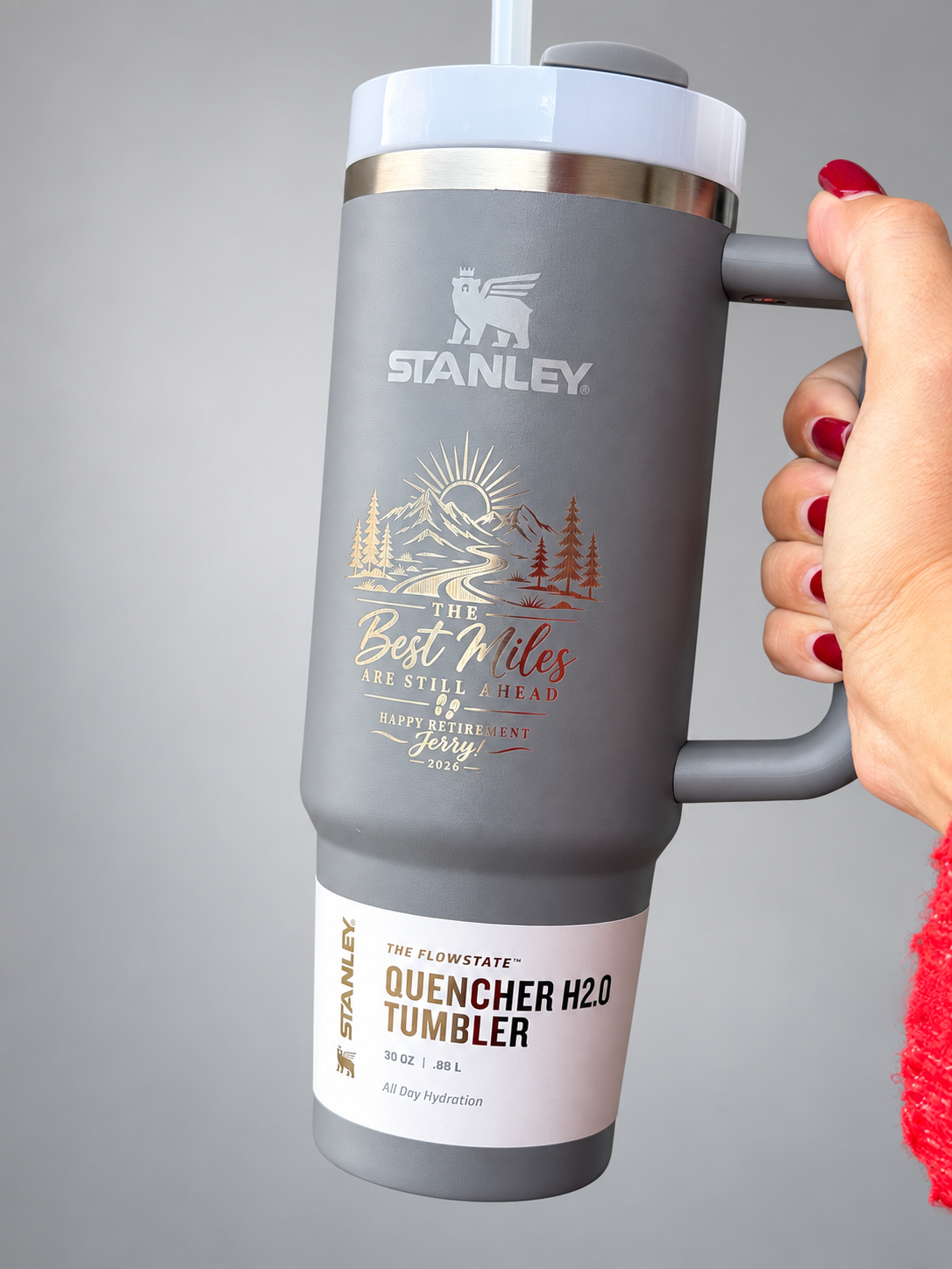 Personalized gray Stanley tumbler with straw on a neutral studio background