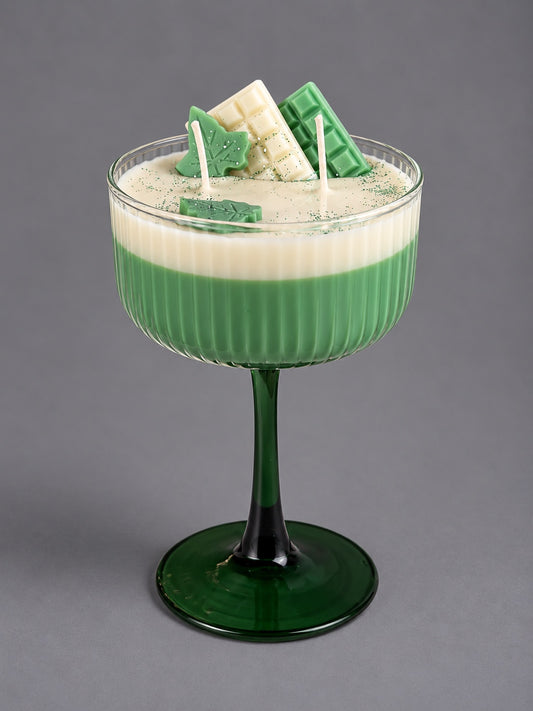 Two-wick matcha cocktail candle in a green stemmed glass with decorative wax pieces