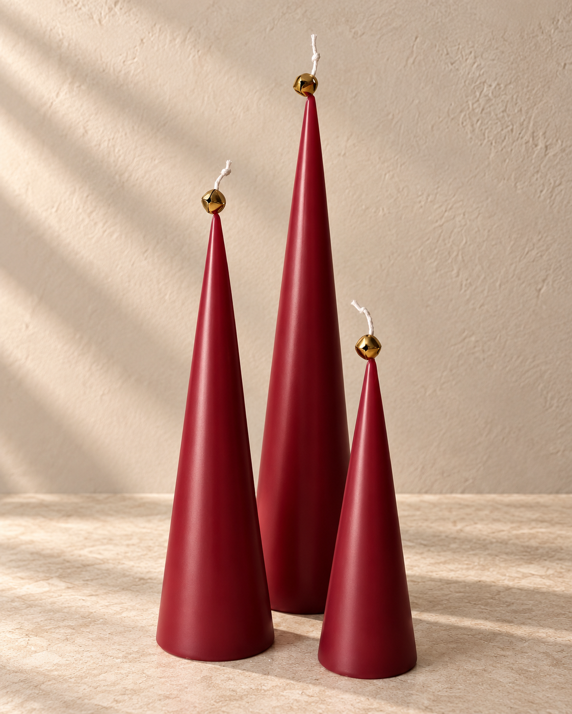 Red cone candle set with gold bells on warm beige stone; digitally styled color preview