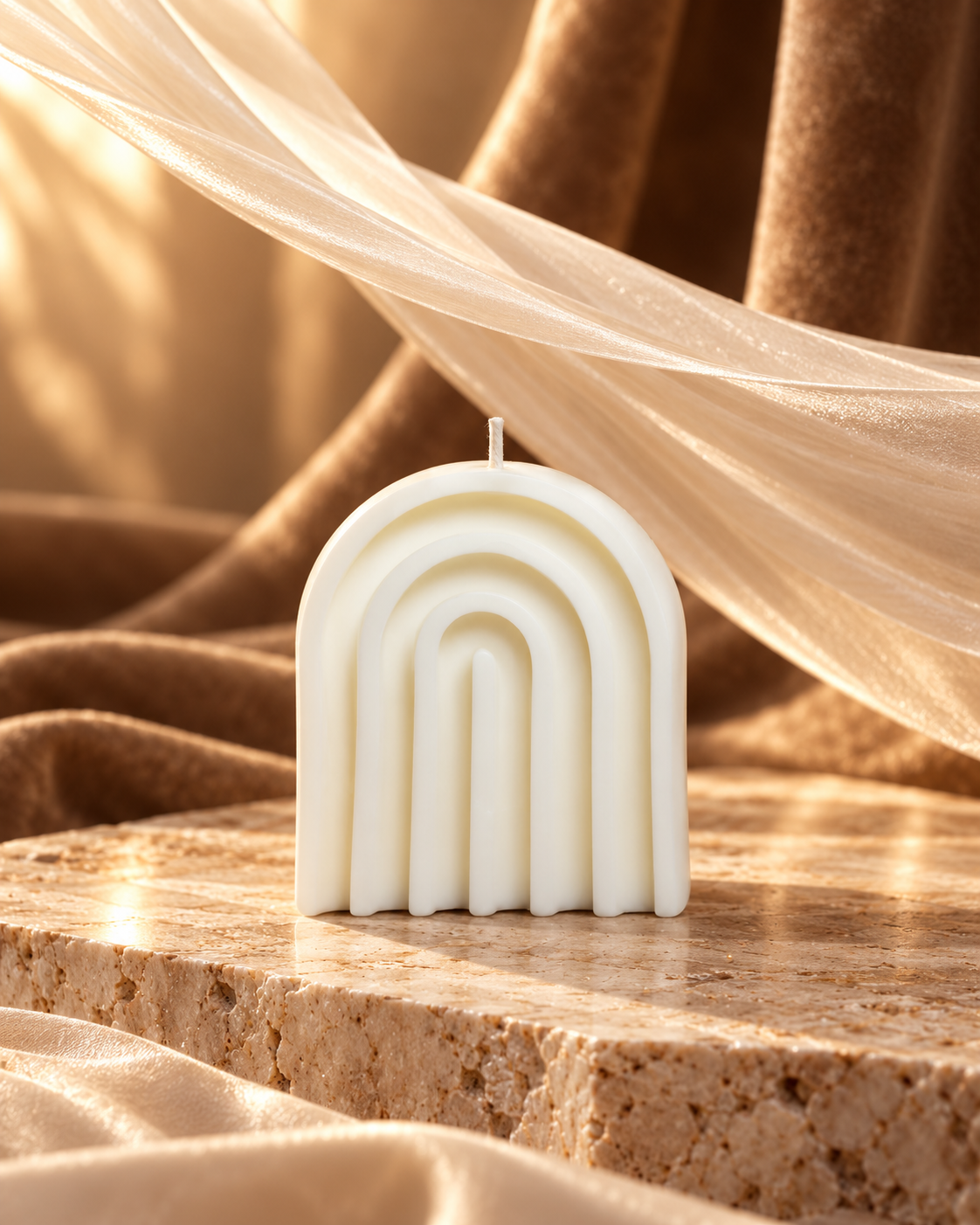 Wide ivory arch candle with nested curved ridges on a stone display block